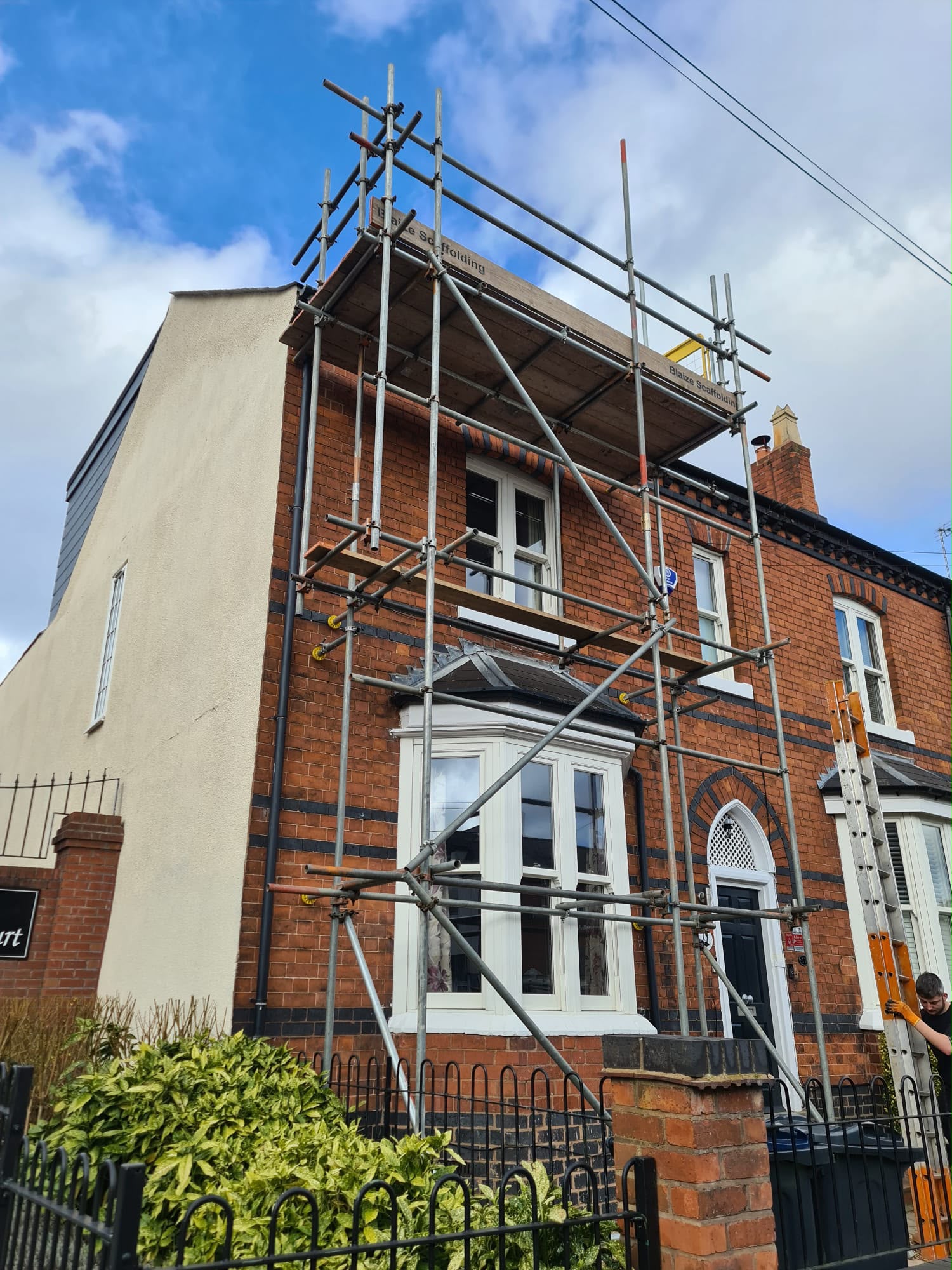 Scaffolding erected on a red-brick end-of-terrace house